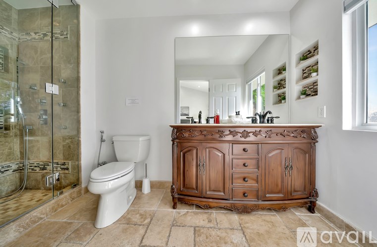 A bathroom with a toilet, a wooden cabinet, and a glass shower stall.