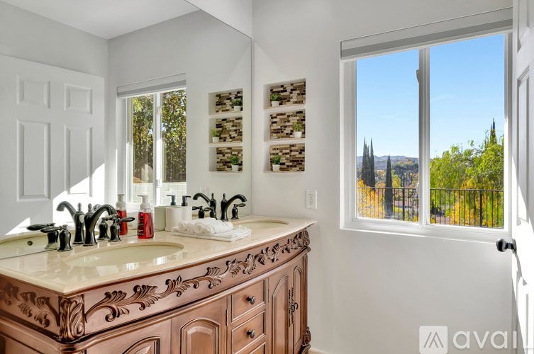 A bathroom with a double sink vanity and a window overlooking a cityscape.