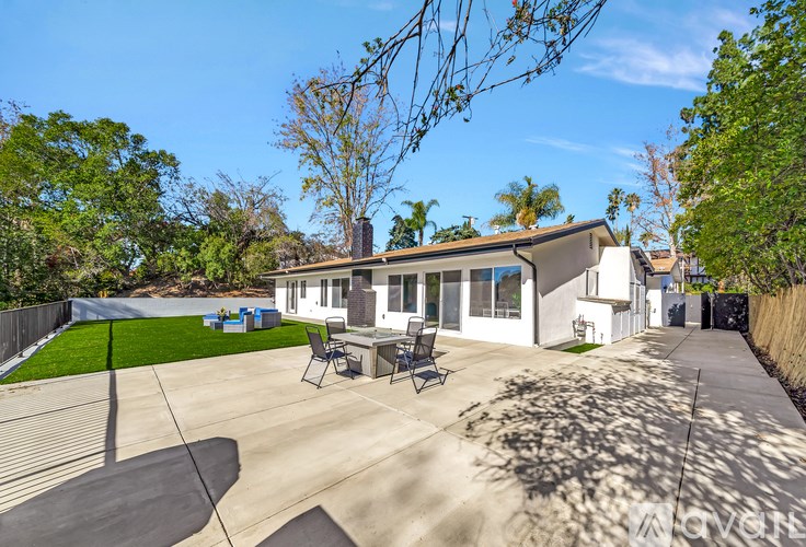 A house with a patio and a tree in the backyard.