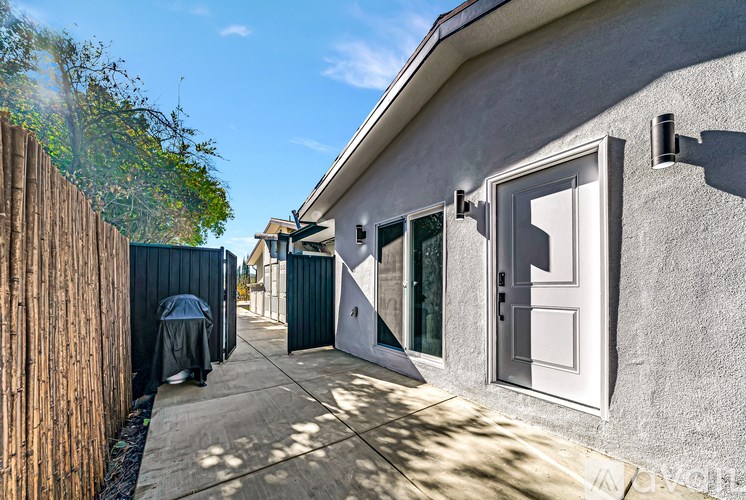 A person is standing in front of a house with a wooden fence.