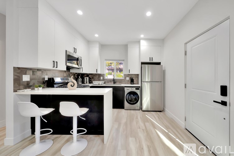 A modern kitchen with white cabinets and a wooden floor.