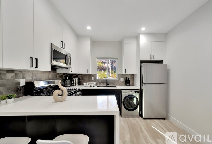 A modern kitchen with white cabinets and a black countertop.