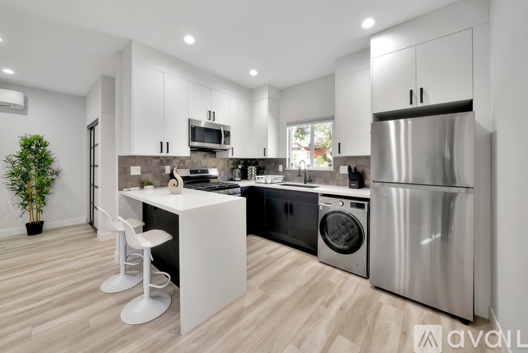 A modern kitchen with a white island and stainless steel appliances.