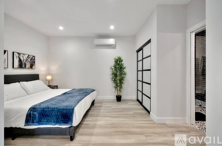 A bedroom with a bed, a plant, and a window.
