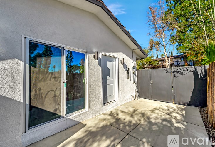 A house with a white door and a window with a reflection of a tree.