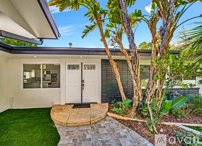A house with a white door and a black mat in front of it.