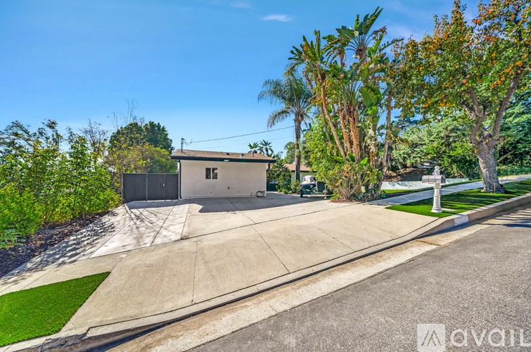 A house with a driveway and trees in front of it.