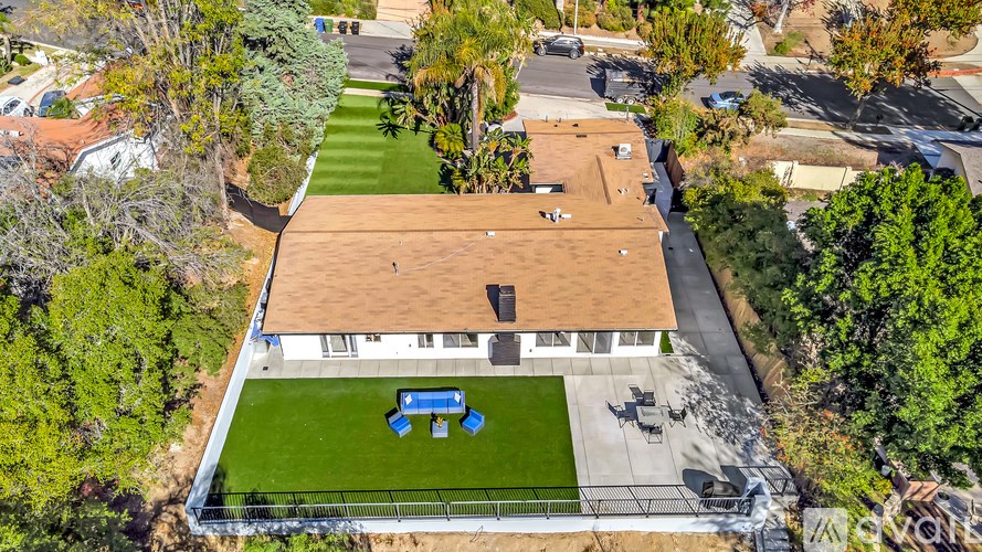 A house with a brown roof and a blue bench in the yard.