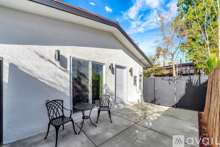 A patio with a table and chairs is in front of a house.