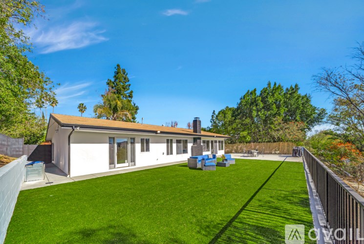 A white house with a brown roof and a green lawn in front.
