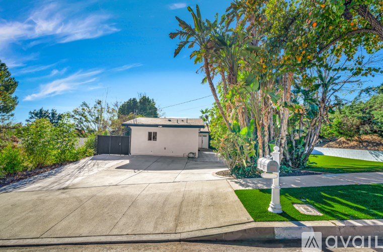A house with a white fence and a tree in front of it.