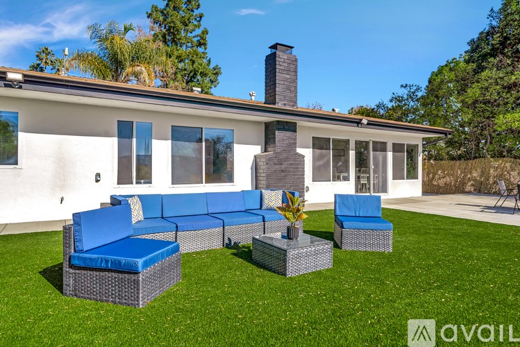 A patio with a blue couch and a table with a vase of flowers on it.