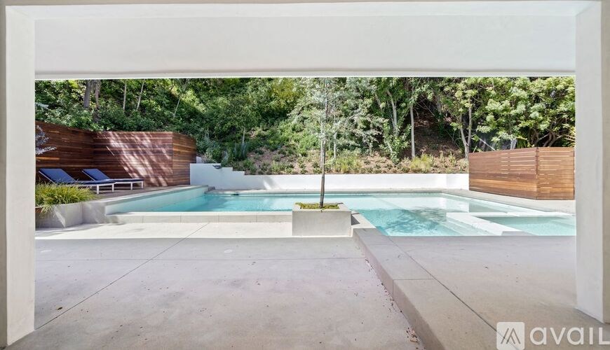 A pool area with a wooden fence and a small waterfall.
