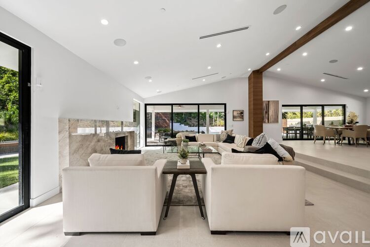 A modern living room with white furniture and a fireplace.