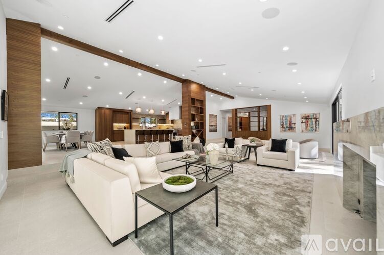 A modern living room with a glass table and white couches.