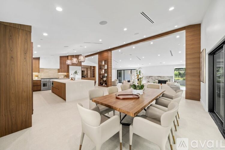 A modern dining room with a wooden table and white chairs.