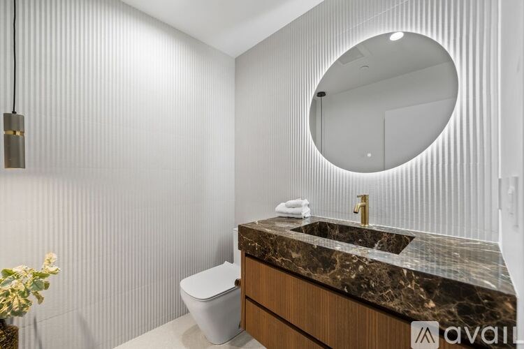 A bathroom with a marble countertop and a round mirror.