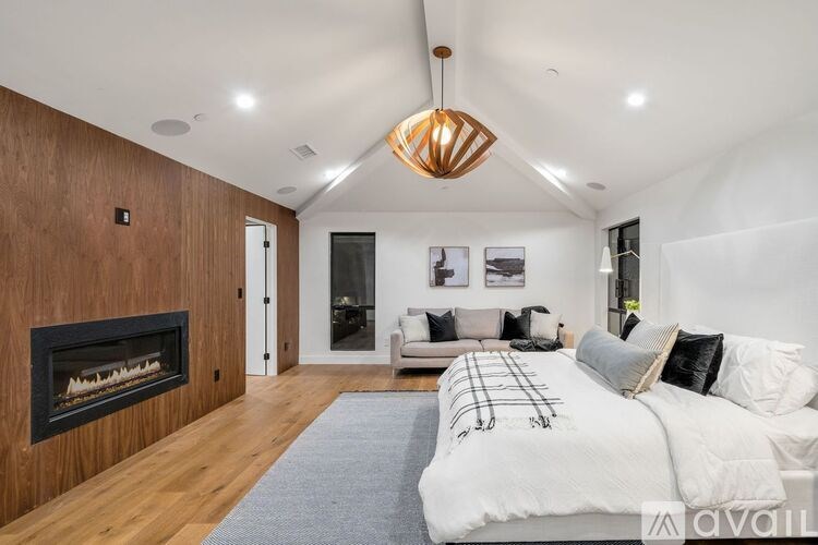 A modern bedroom with a fireplace and a large bed.