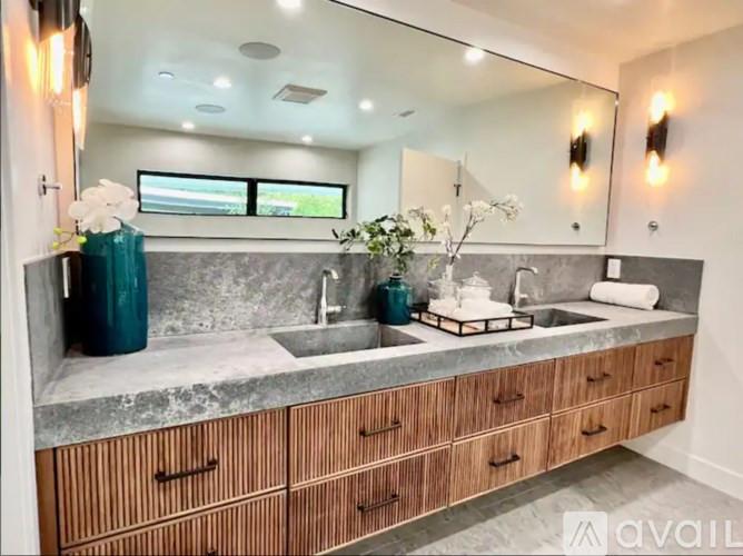 A modern bathroom with a marble countertop and wooden drawers.