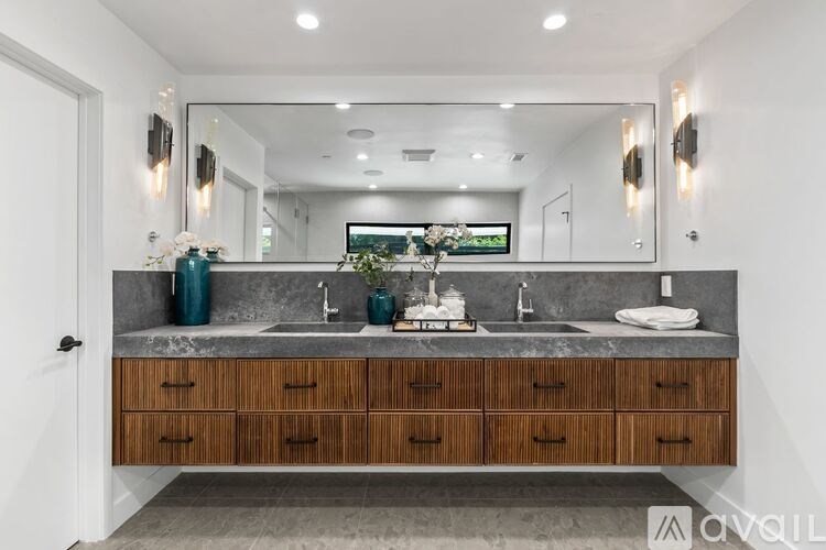 A bathroom with a sink, mirror, and wooden drawers.