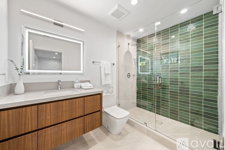 A modern bathroom with a toilet, sink, and glass shower.