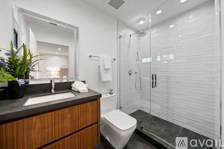 A modern bathroom with a wooden vanity and a walk-in shower.