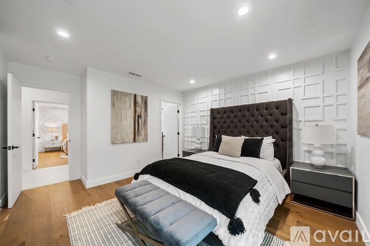 A bedroom with a large bed and a black tufted headboard.