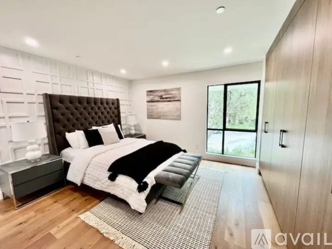 A modern bedroom with a large bed and a large window.