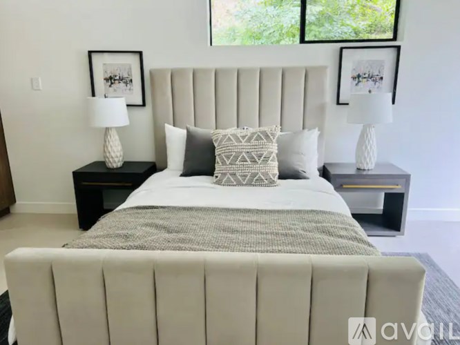 A bed with a white headboard and pillows is in the center of the image.