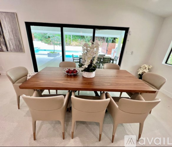 A dining table with chairs and a vase of flowers on it.