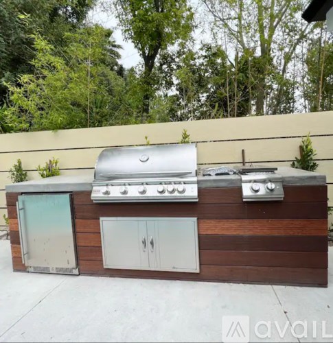 A wooden outdoor kitchen with a grill and cabinet.