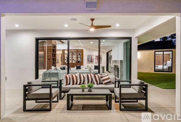 A patio with a couch, chairs, and a ceiling fan.