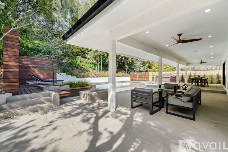 A modern outdoor living space with a ceiling fan and seating area.