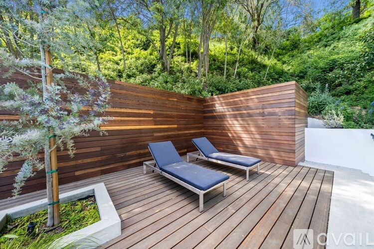 A wooden deck with two lounge chairs and a small garden area.