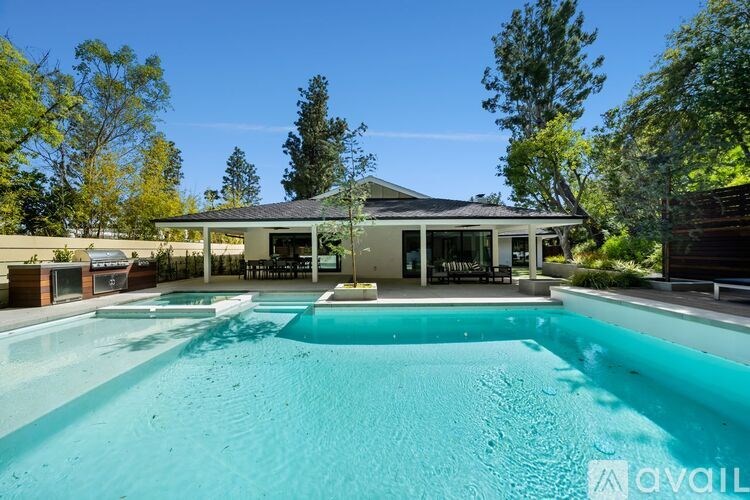 A large swimming pool in front of a house with a sign that says "available".