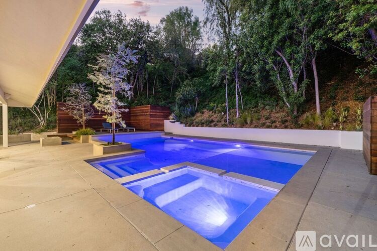 A swimming pool surrounded by a concrete patio and a wooden fence.
