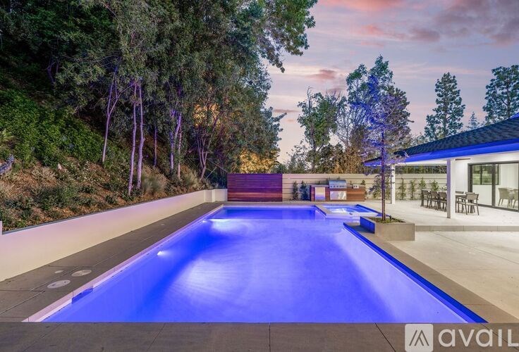 A swimming pool surrounded by trees and a building with the word "available" on it.