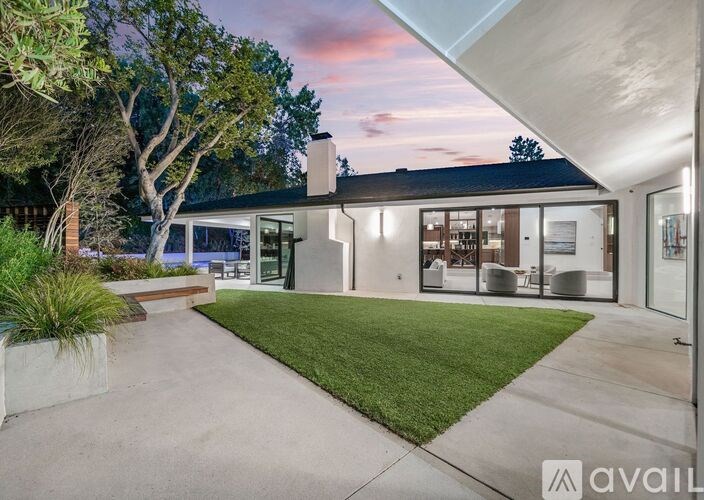 A modern house with a large front yard and a tree.