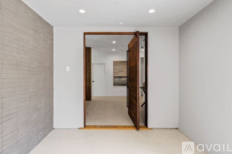 A hallway with a wooden door and a brick wall on the left.