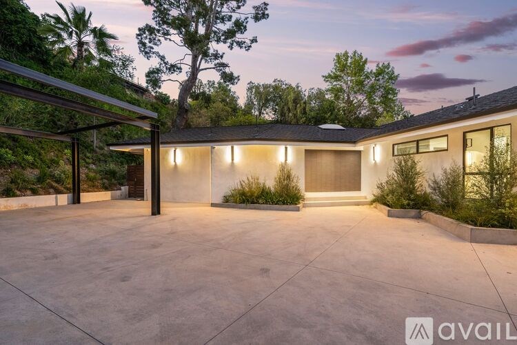 A house with a driveway and a tree in front of it.