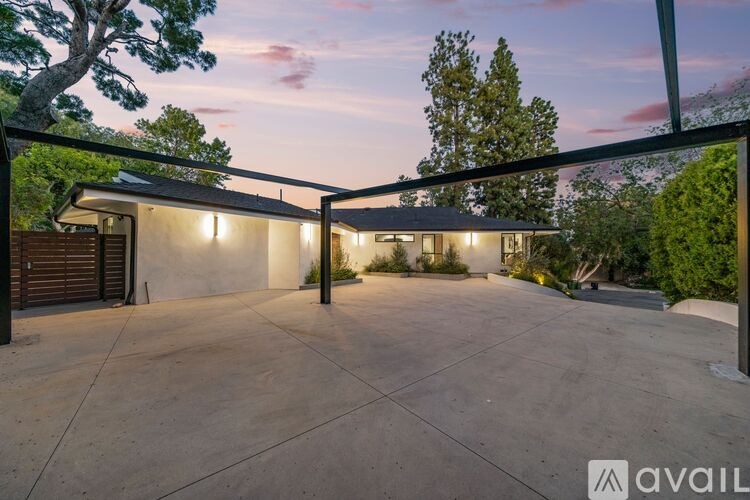 A modern house with a large driveway and a tree in the front yard.