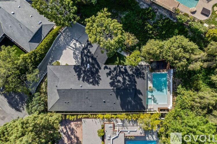 A bird's eye view of a house with a pool surrounded by trees.