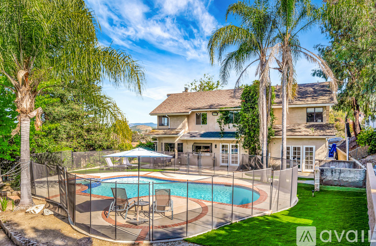 A house with a pool surrounded by a fence and trees.