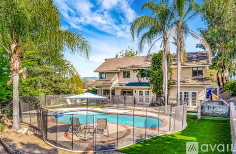 A house with a pool surrounded by a fence and trees.