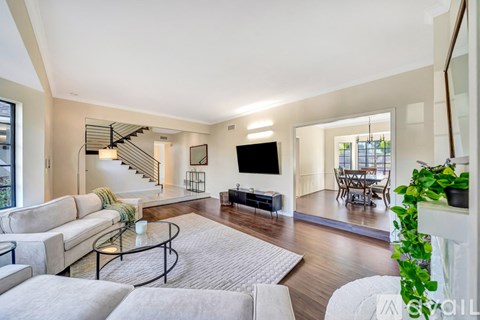 A living room with a white couch and a glass coffee table.