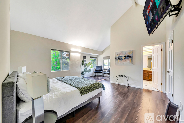 A bedroom with a large bed and a flat screen TV mounted on the wall.