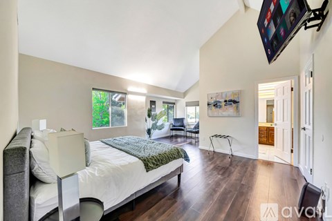 A bedroom with a large bed and a flat screen TV mounted on the wall.