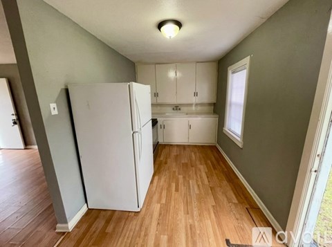 A kitchen with a white refrigerator and wooden floors.