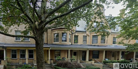 A tree in front of a building with a sign that says "available".