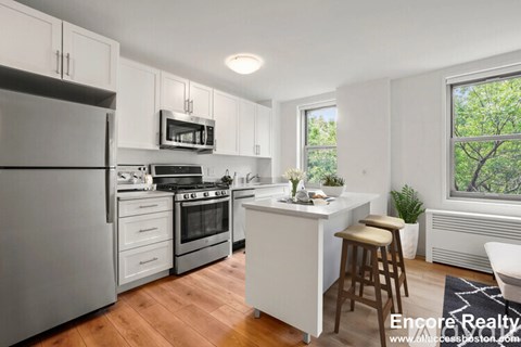 A kitchen with white cabinets and a white refrigerator.